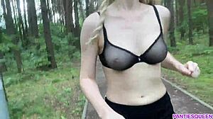 Blonde Frau trainiert im Freien im Park und zeigt ihren nackten Körper und ihre hüpfenden Brüste